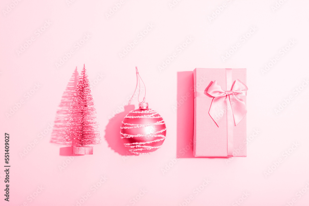 Gift box, Christmas ball and fir tree toy on pink background with sharp shadows. Minimal composition. Top view, flat lay
