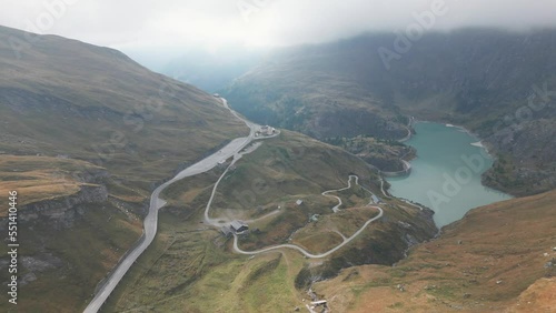 Alpine roads in Heilingenblut, Austria on a foggy day. Serpentine roads in the mountains, with Alpine Lake in the background. Cloudy day in Carinthia, Southern Austria, captured by drone in 4k, 24fps. photo