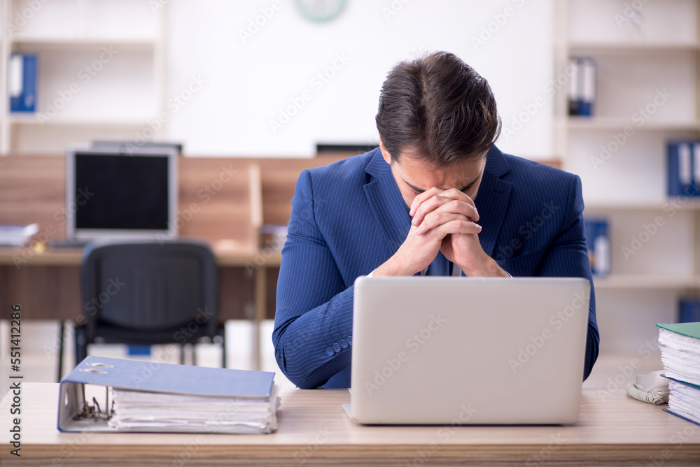 Young male employee and too much work in the office Young male employee and too much work in the office