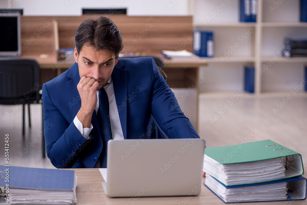 Young male employee and too much work in the office Young male employee and too much work in the office
