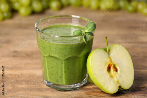 Glass of fresh green smoothie and cut apple on wooden table