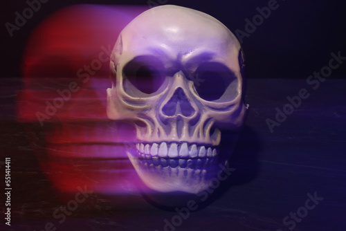 Human skull in neon lights on dark grey table