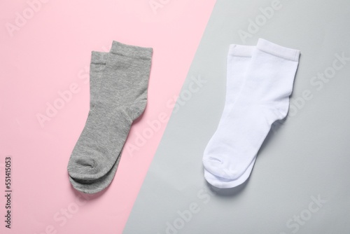 White and grey socks on color background, flat lay