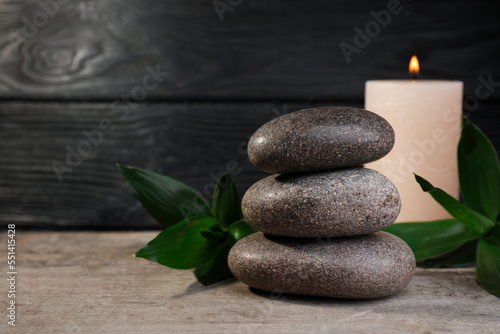 Stacked spa stones  bamboo and candle on wooden table. Space for text