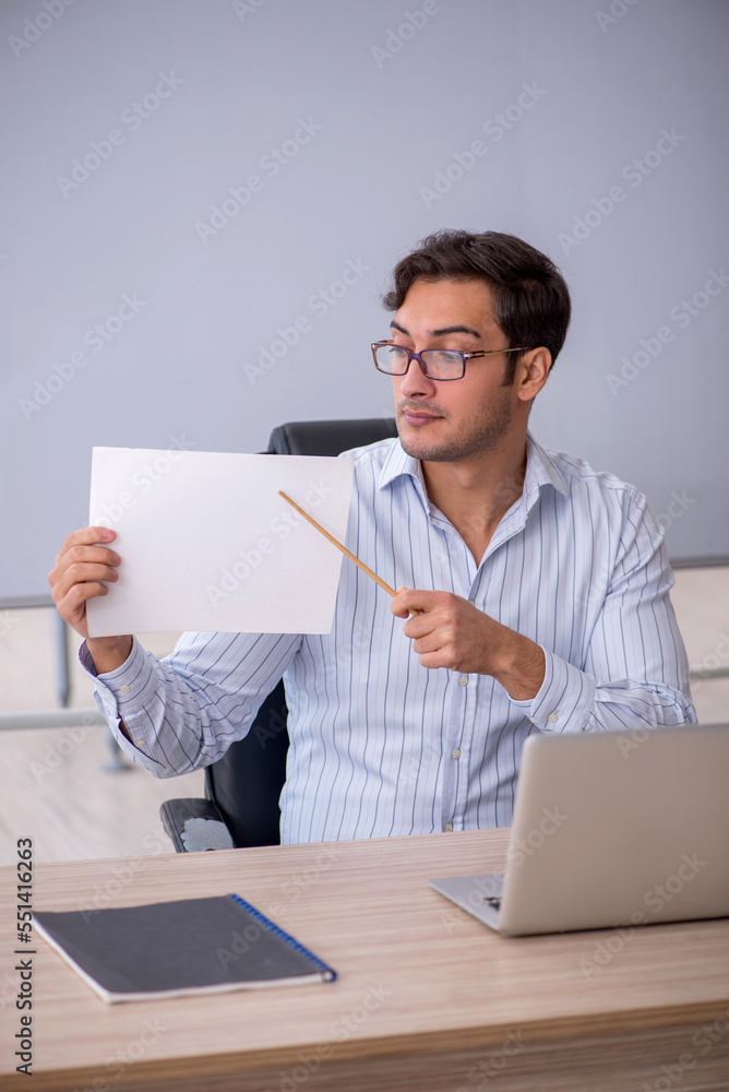 Young male teacher sitting in the classroom Young male teacher sitting in the classroom
