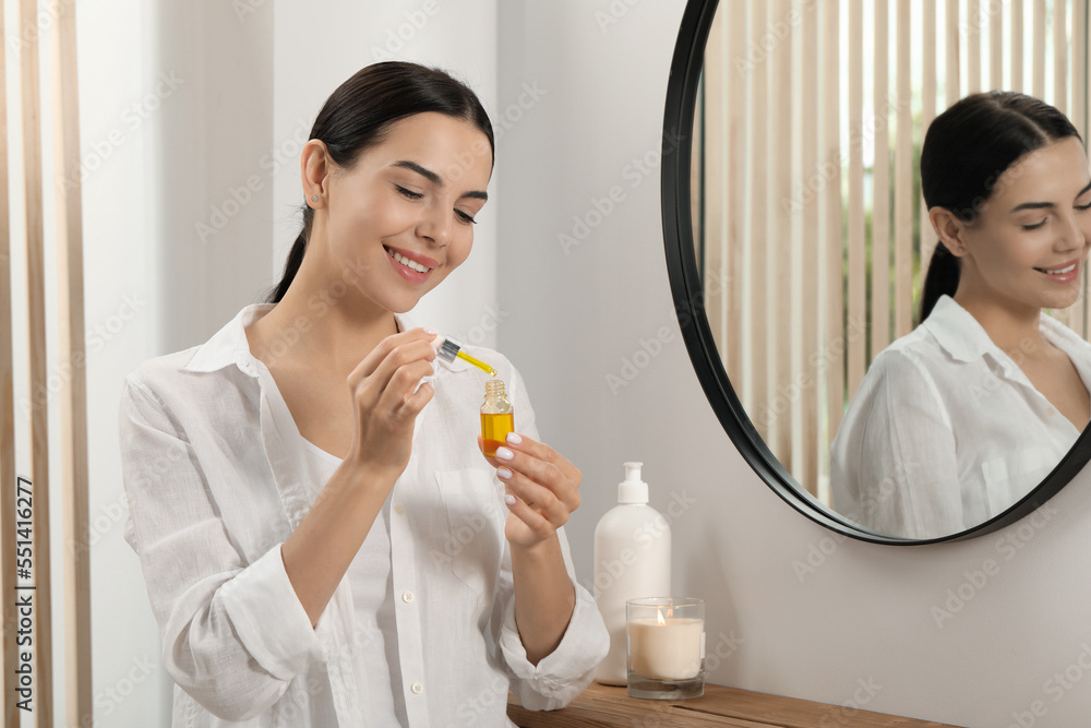 Young woman with bottle of essential oil indoors Young woman with bottle of essential oil indoors