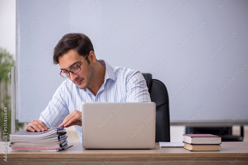 Young male teacher sitting in the classroom Young male teacher sitting in the classroom