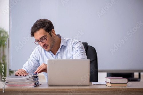 Young male teacher sitting in the classroom