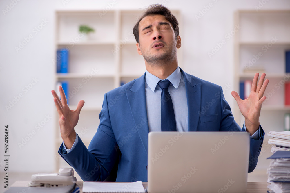 Young male employee and too much work in the office Young male employee and too much work in the office