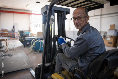 A worker drives the mechanical forklift during work in the warehouse.
