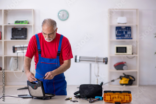 Old repairman repairing sandwich maker at workshop