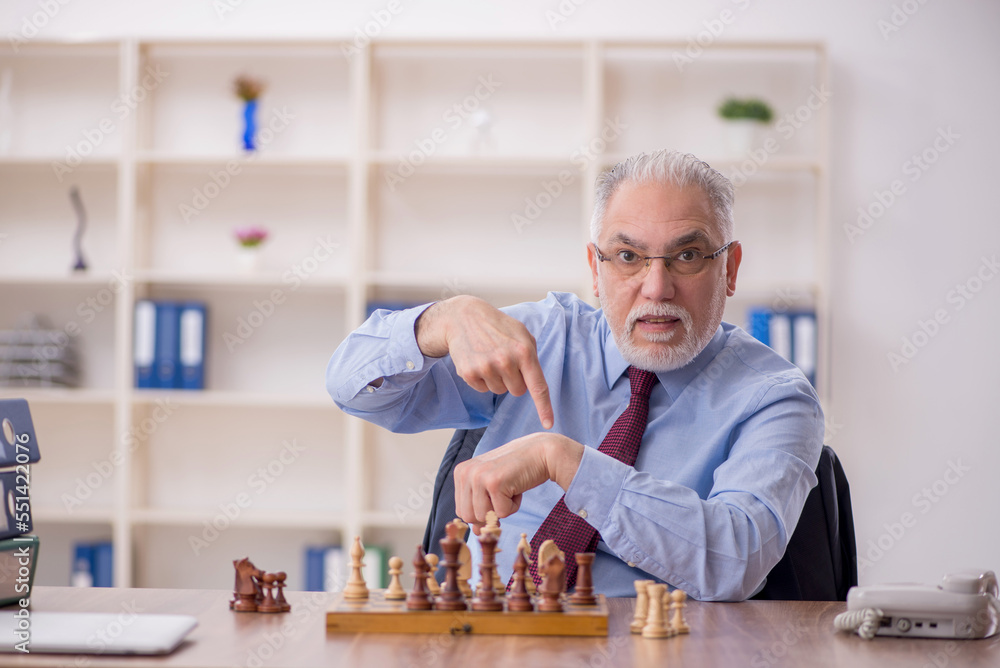 Old businessman employee playing chess at workplace Old businessman employee playing chess at workplace