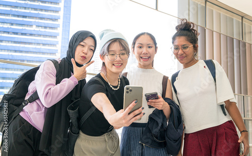 Young multi-racial women smiling and taking group selfie together with a smartphone.