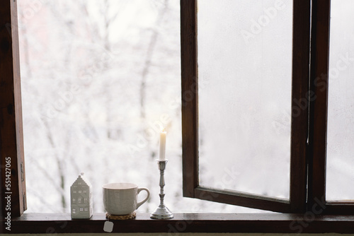 Cozy winter still life. Cup of hot tea with a candle and home decor on a vintage wooden windowsill. Cozy home concept. Sweet home.
