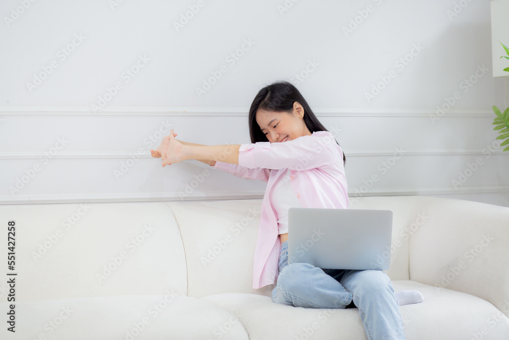 Beautiful young asian businesswoman sitting on sofa and working from home and break while stretch arm for relax in living room at home, woman is freelance working on laptop computer, business concept. Beautiful young asian businesswoman sitting on sofa and working from home and break while stretch arm for relax in living room at home, woman is freelance working on laptop computer, business concept.