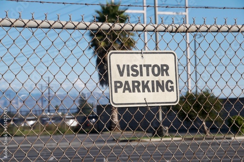 Sign visitor parking on wire link fence black white