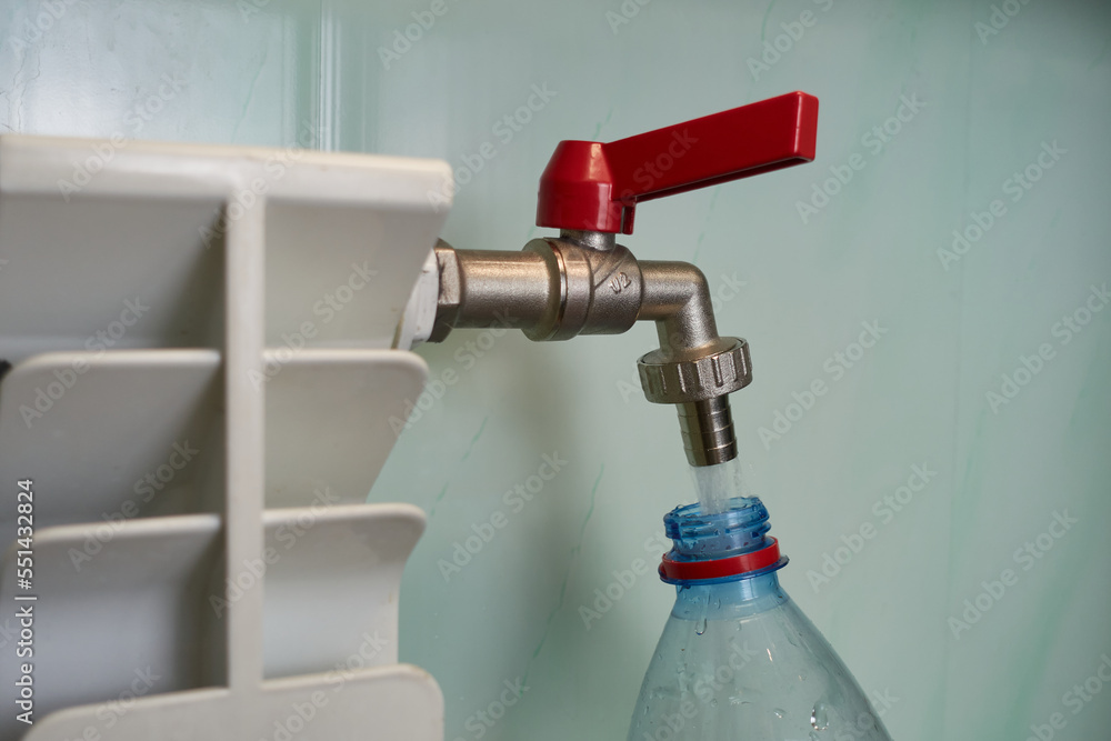 Water is taken from the radiator. From the heating element, water is drawn from the tap into a plastic bottle. Water is taken from the radiator. From the heating element, water is drawn from the tap into a plastic bottle.