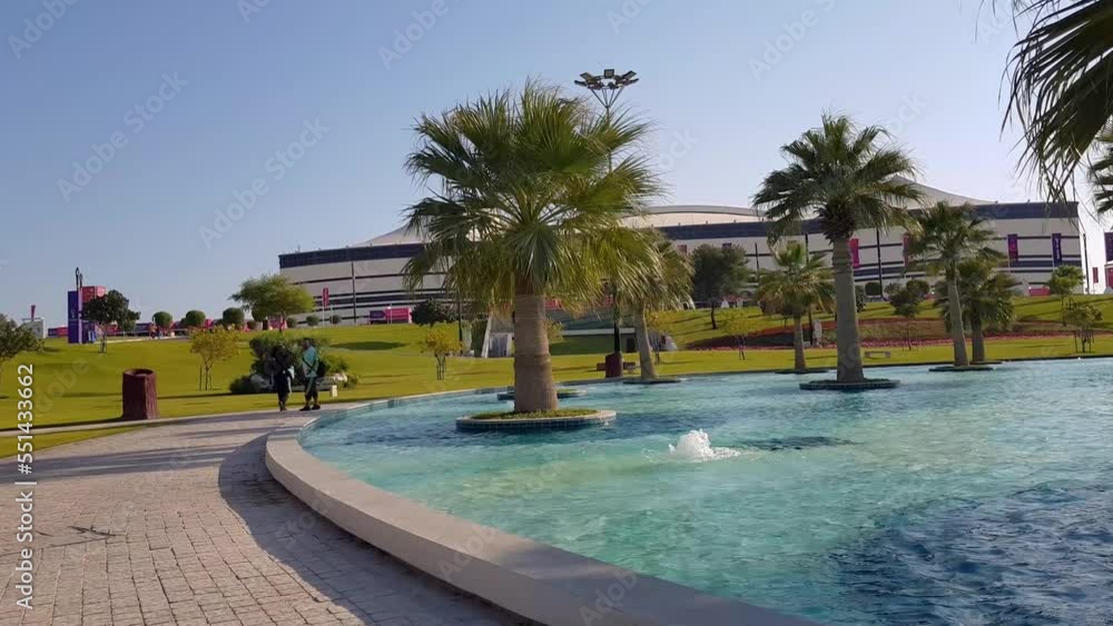 A couple are walking beside a beautiful lake in al bayt vip entrance al bayt stadium in doha qatar fifa world cup to host an exciting match in a sunny day near the sun set. Scenic fountain palm tree A couple are walking beside a beautiful lake in al bayt vip entrance al bayt stadium in doha qatar fifa world cup to host an exciting match in a sunny day near the sun set. Scenic fountain palm tree