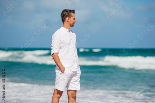 Young man in white walking on the beach © travnikovstudio
