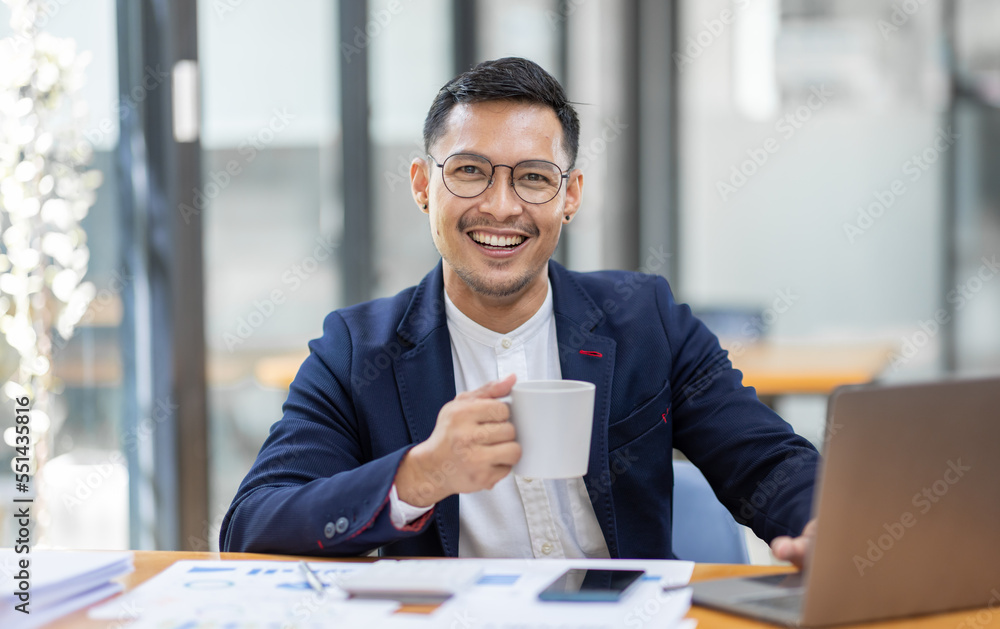 Young business Asian man working at workplace with laptop and papers on desk Young business Asian man working at workplace with laptop and papers on desk