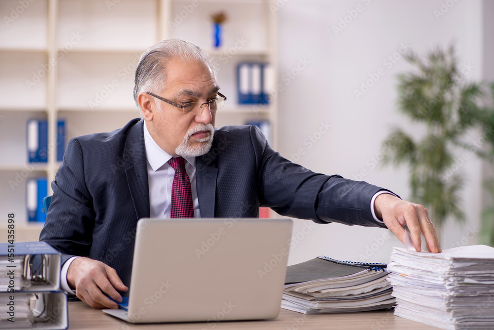 Old male employee sitting at workplace Old male employee sitting at workplace