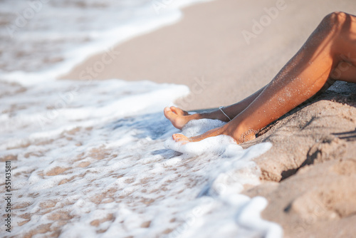 Closeup of woman legs splashing in shallow water on the beach