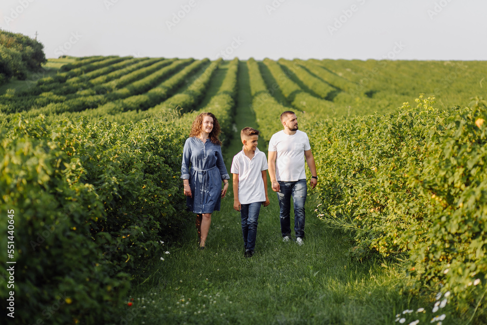 Young family looking at the camera while walking in the garden Young family looking at the camera while walking in the garden