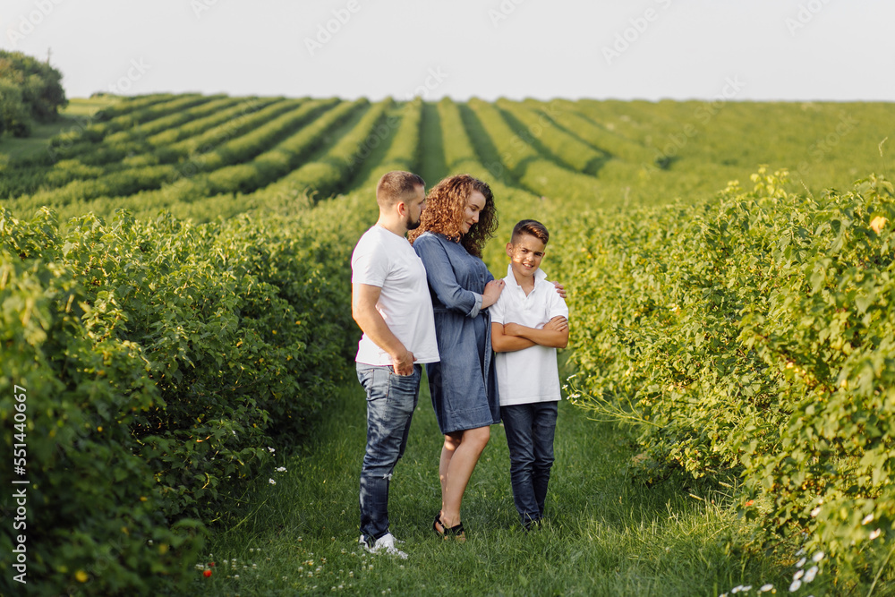 Young family looking at the camera while walking in the garden Young family looking at the camera while walking in the garden