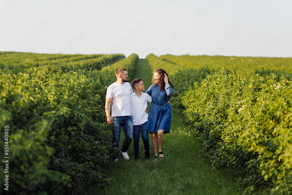 Young family looking at the camera while walking in the garden Young family looking at the camera while walking in the garden