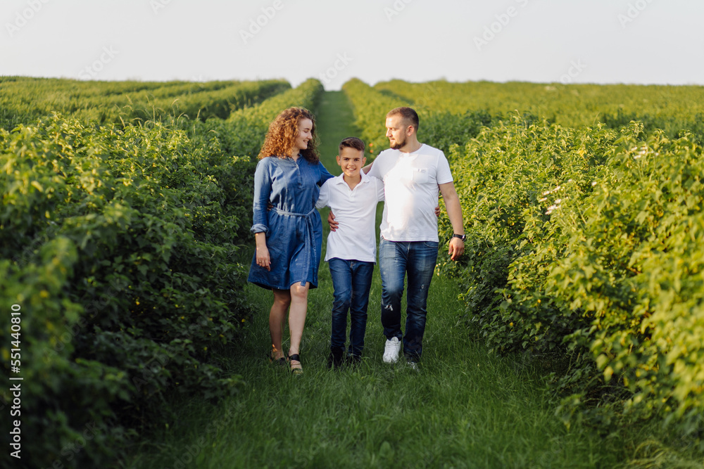 Fototapeta premium Young family looking at the camera while walking in the garden
