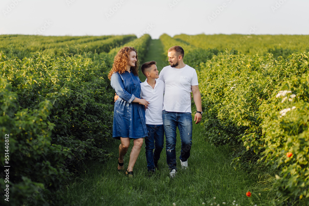 Young family looking at the camera while walking in the garden Young family looking at the camera while walking in the garden
