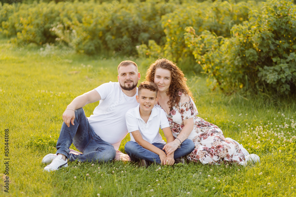 Fototapeta premium Young family looking at the camera while walking in the garden