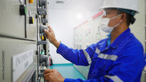 An electrical maintenance worker working in a station building inspects an electrical control panel to maintain the stability of the voltage supply to industrial plant. Energy industrial concept