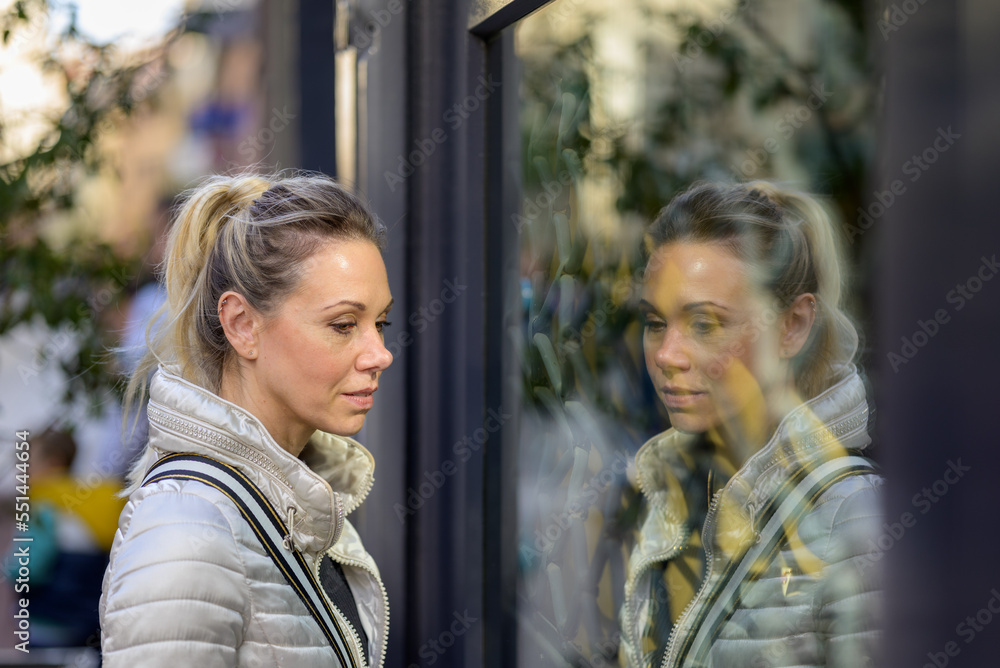 Side view of a woman looking through the window of a shop