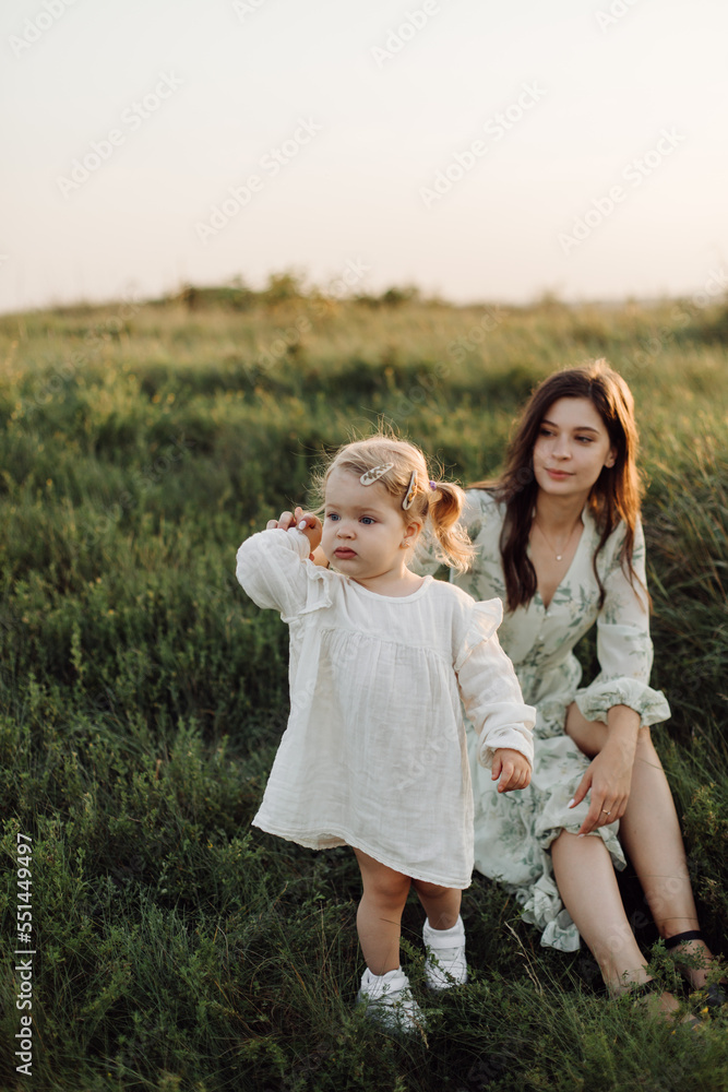Beautiful caucasian family of father, mother and little daughter posing on camera on background of green field Beautiful caucasian family of father, mother and little daughter posing on camera on background of green field