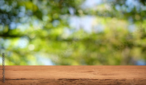 Empty wooden table are placed outdoors on green bokeh from natural leaves and sunlight. Counter display concept