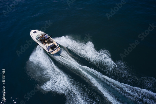 Speedboat with people in diagonal motion. White boat fast movement on dark water, white trail on the water. © Berg