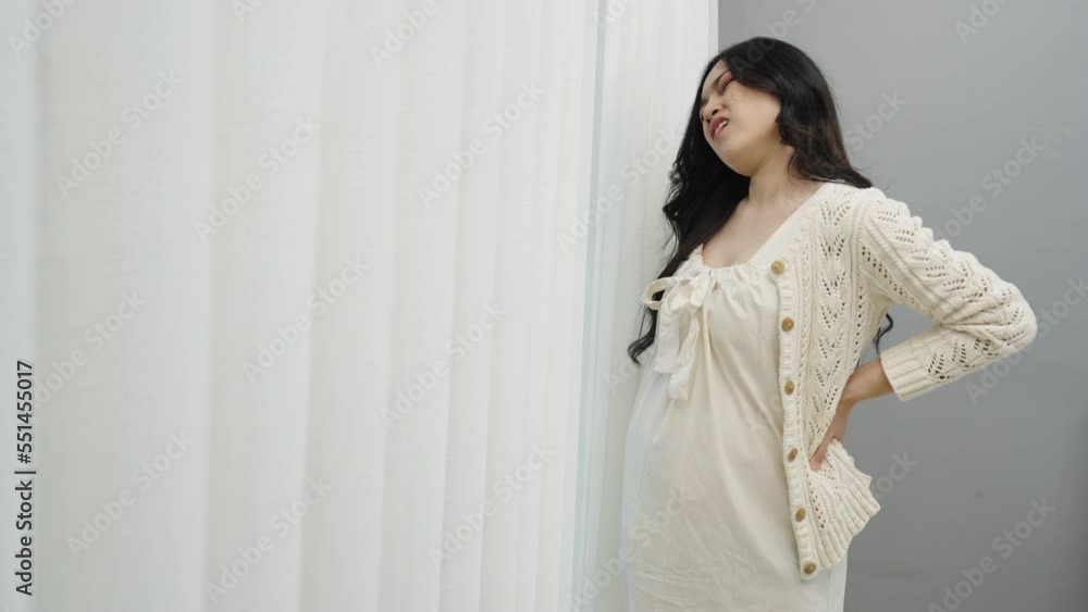 pregnant woman suffering lower back pain near the window pregnant woman suffering lower back pain near the window