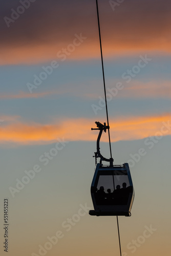 Obraz na plátně Cable car cabin with silhouettes of people against the background of the sunset