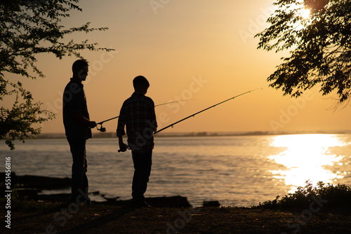silhouette of man and teen boy fishing on the lake