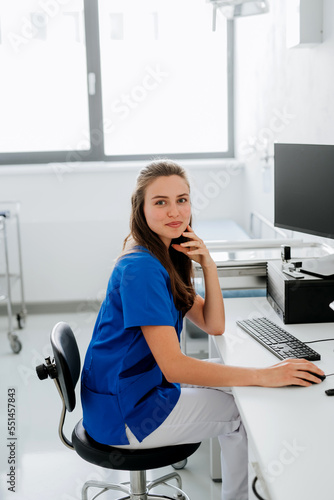 Young woman doctor sitting at hospital office desk. photo