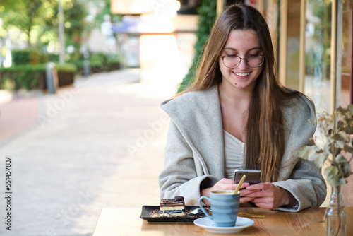 Smiling woman using the smartphone in a coffee shop.