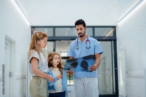 Fototapeta Naklejka Na Ścianę i Meble -  Young multiracial doctor talking with mother of little girl at hospital corridor.