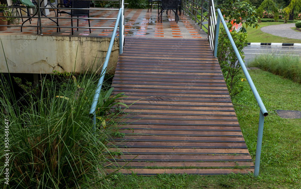Fototapeta premium Disabled way in front of building. Handicapped traffic symbol on the floor in front of ramp way for support wheelchair. Disabled way in front of cafe on green nature landscape.