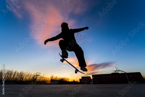 In the evening, a boy is playing skateboard.