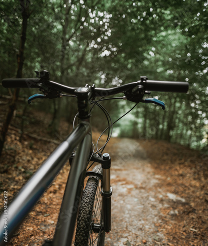 Mountain bike handlebar viewed from the first-person perspective.handlebar and the forest trail. Concept of spending time outdoors while bikeriding © AlexGo