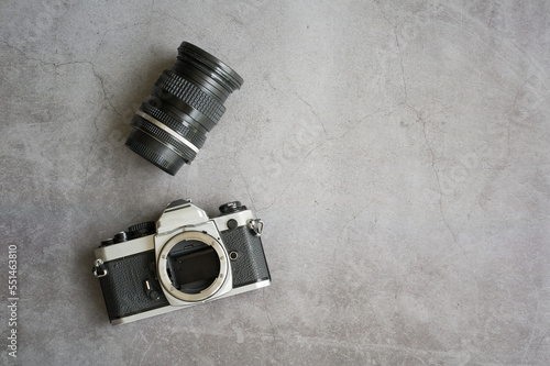 Vintage old camera and lens on cement floor background. Film camera retro style 1970s. Top view with copy space for any design.