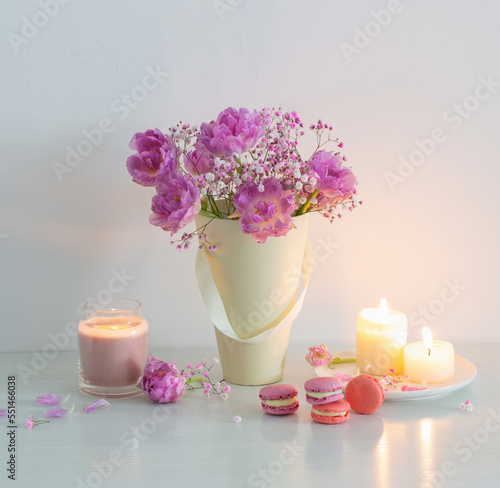 bouquet of pink spring flowers and burning candles on  white table