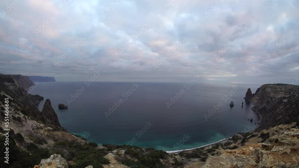 Panoramic sunset cloudy sky over the sea with rocky volcanic cliff. Abstract nature summer ocean sea background. Small waves on golden warm water surface with bokeh lights from sun. Panoramic sunset cloudy sky over the sea with rocky volcanic cliff. Abstract nature summer ocean sea background. Small waves on golden warm water surface with bokeh lights from sun.