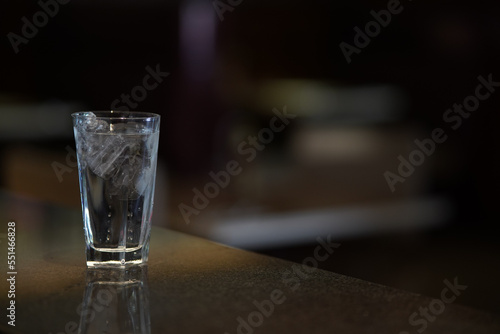 A glass of water with ice on a dark environment, low key light photography 